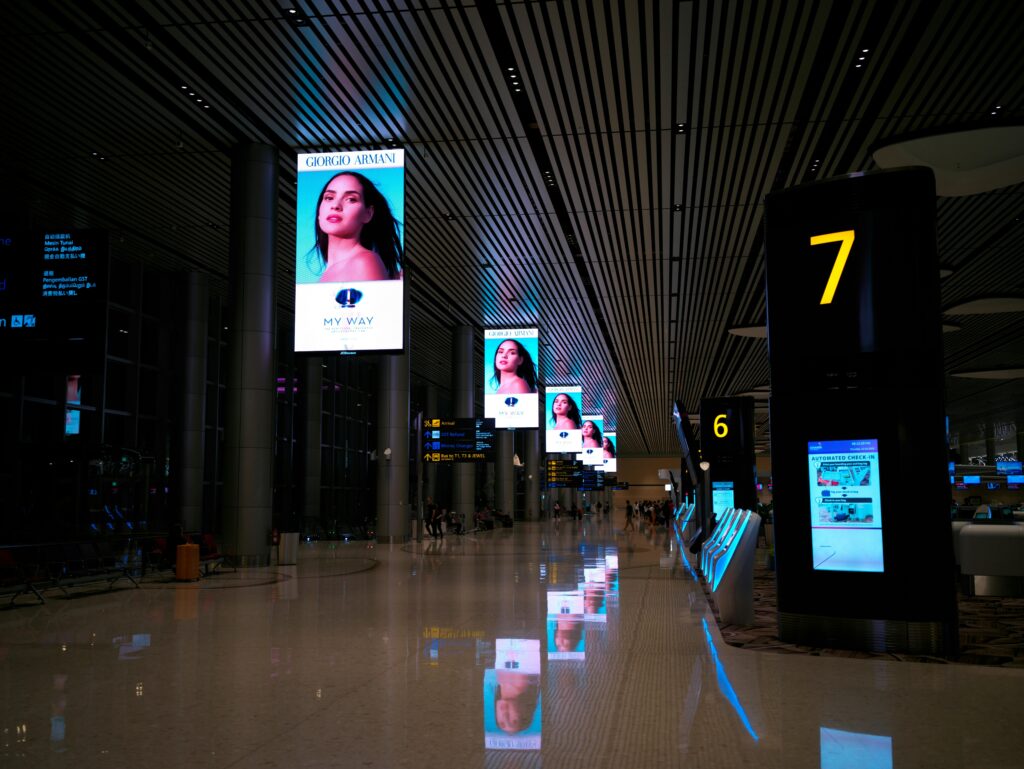 Multiple digital displays in an airport terminal showing advertisements and information screens, highlighting Norbrite’s commercial display capabilities